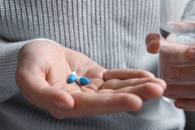 Man with glass of water and pills, closeup