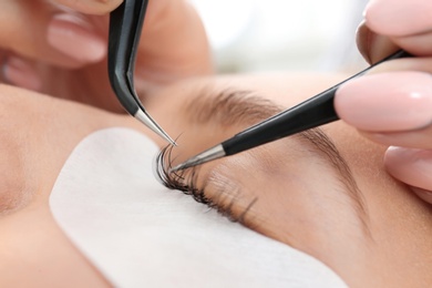 Young woman undergoing eyelash extensions procedure, closeup