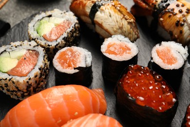 Photo of Set of delicious sushi rolls on slate board, closeup