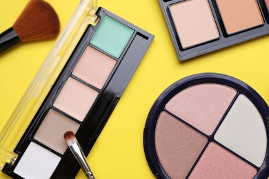 Different contouring palettes and brushes on yellow background, flat lay. Professional cosmetic product
