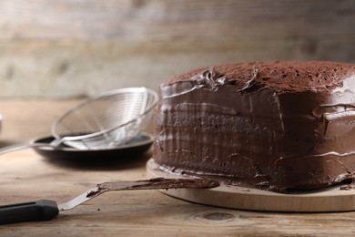 Photo of Delicious homemade layer cake with chocolate cream on wooden table, closeup