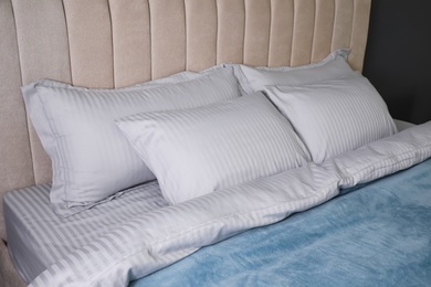 Comfortable bed with soft blanket and pillows, closeup