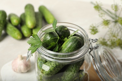 Photo of Pickling jar with fresh cucumbers on light table, closeup