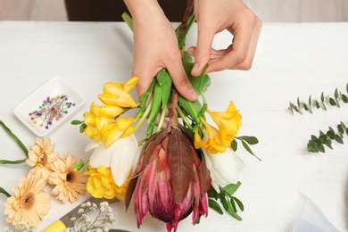 Female florist making beautiful bouquet at table