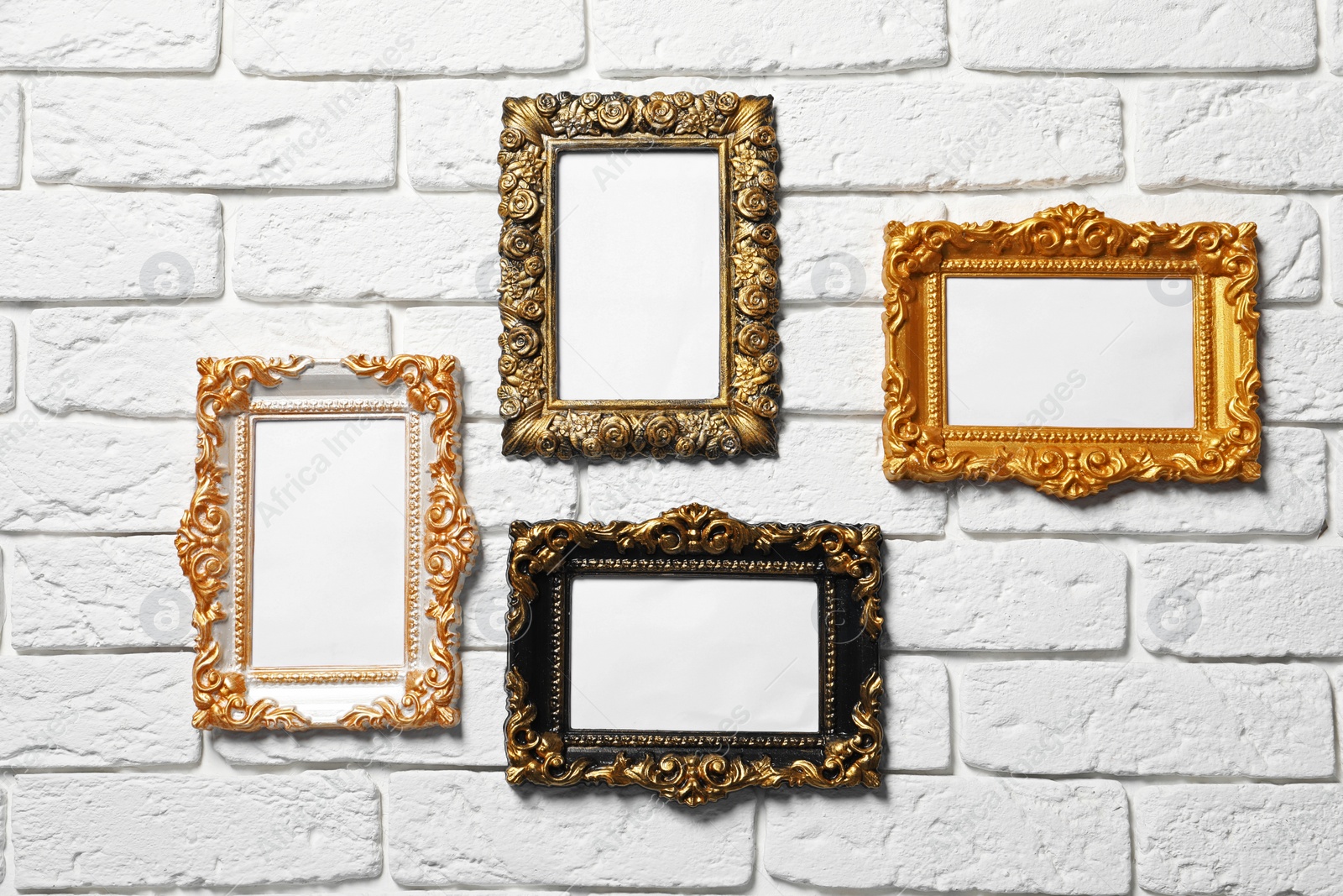 Photo of Blank vintage frames hanging on white brick wall. Mockup for design