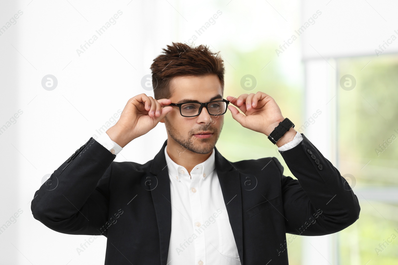 Photo of Portrait of handsome young man in elegant suit with glasses indoors