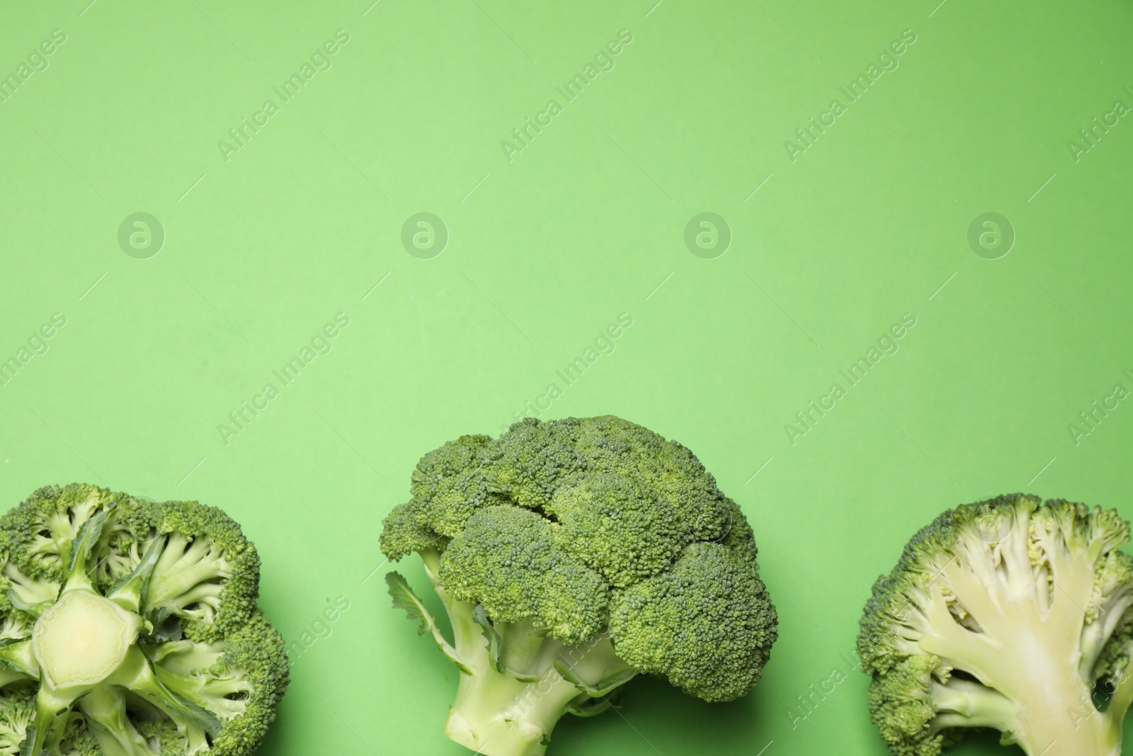 Photo of Fresh broccoli on green background, flat lay. Space for text