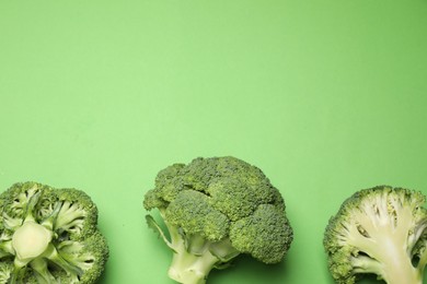 Fresh broccoli on green background, flat lay. Space for text