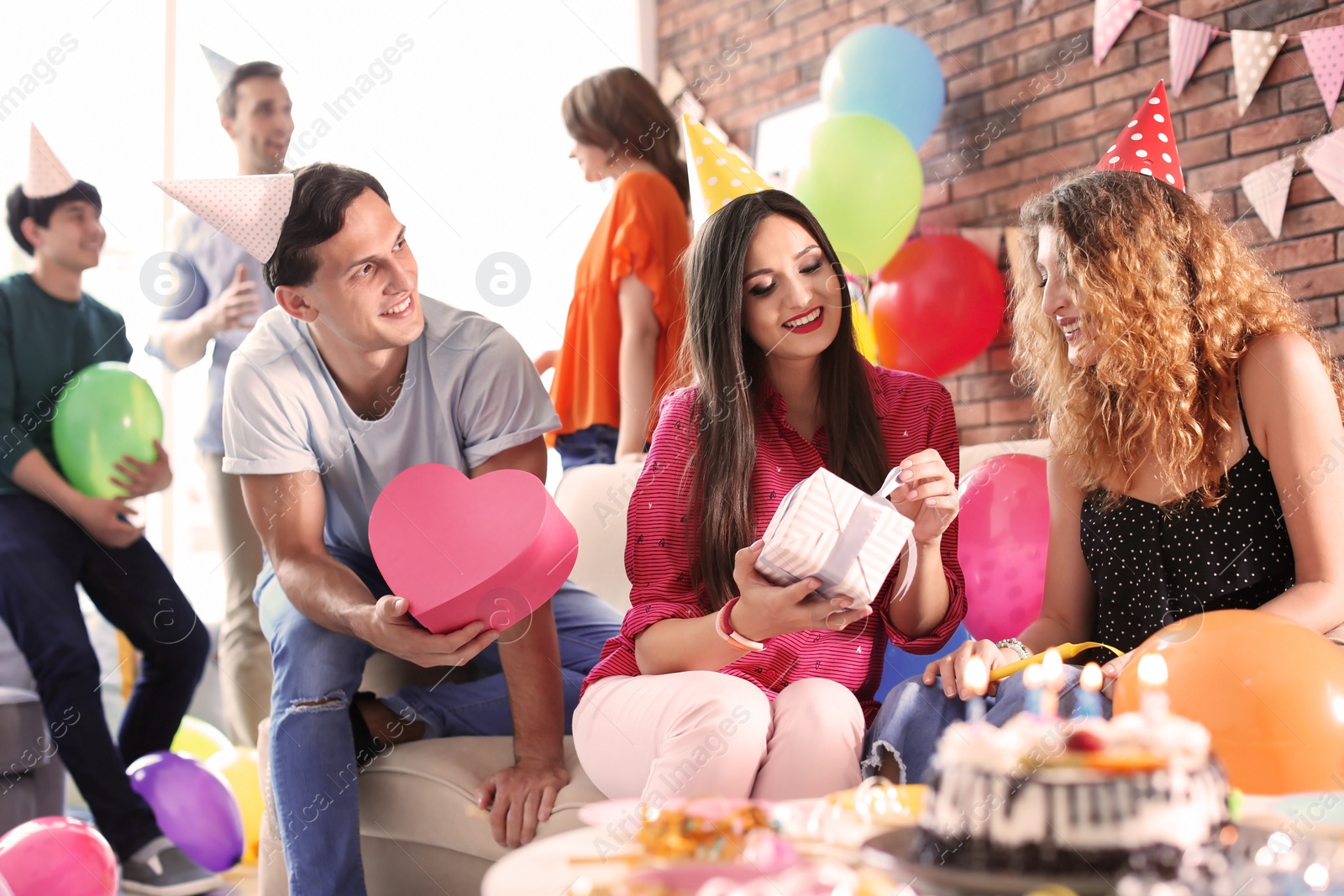 Photo of Young people having birthday party in decorated room