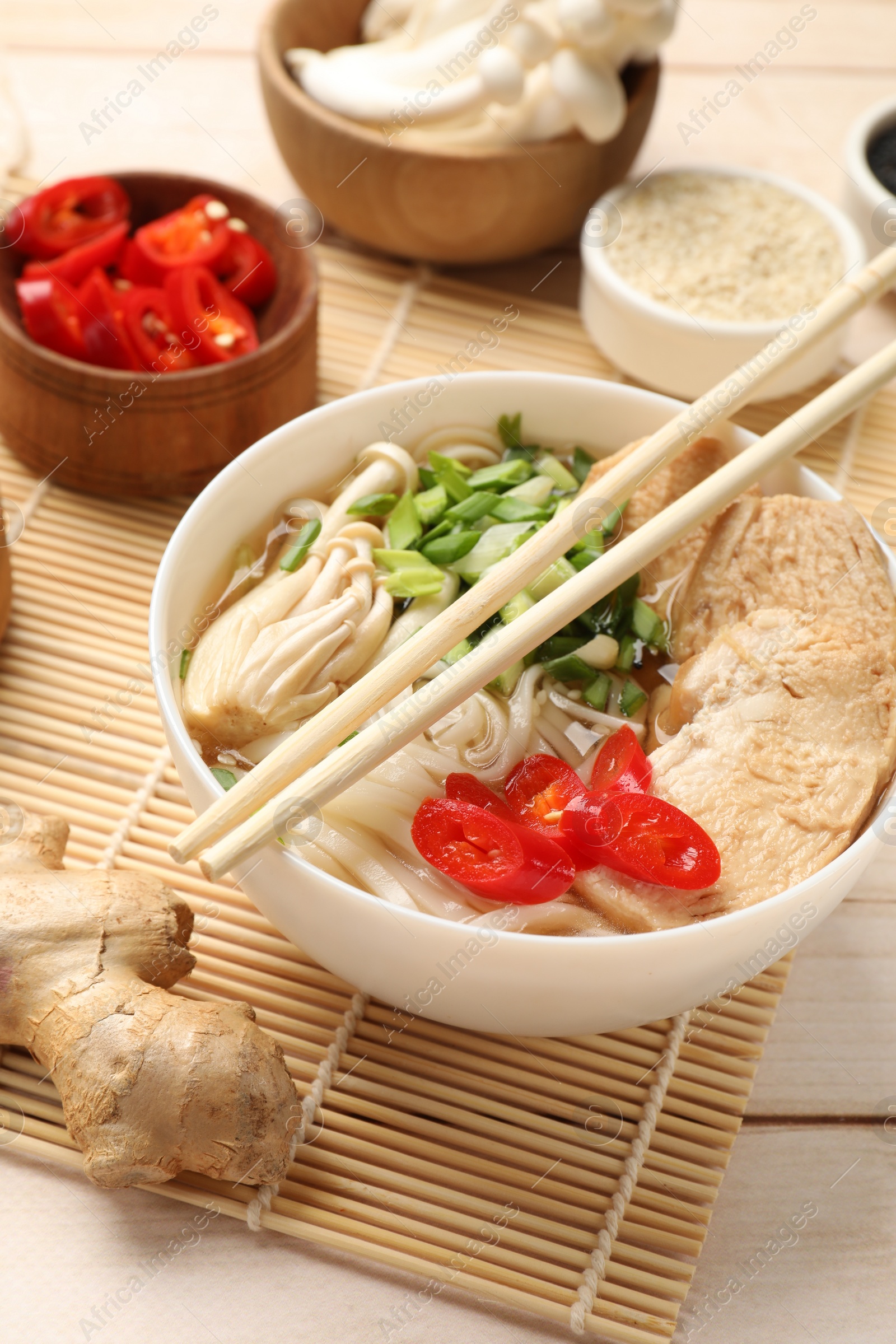 Photo of Delicious ramen with meat and ingredients on white wooden table. Noodle soup