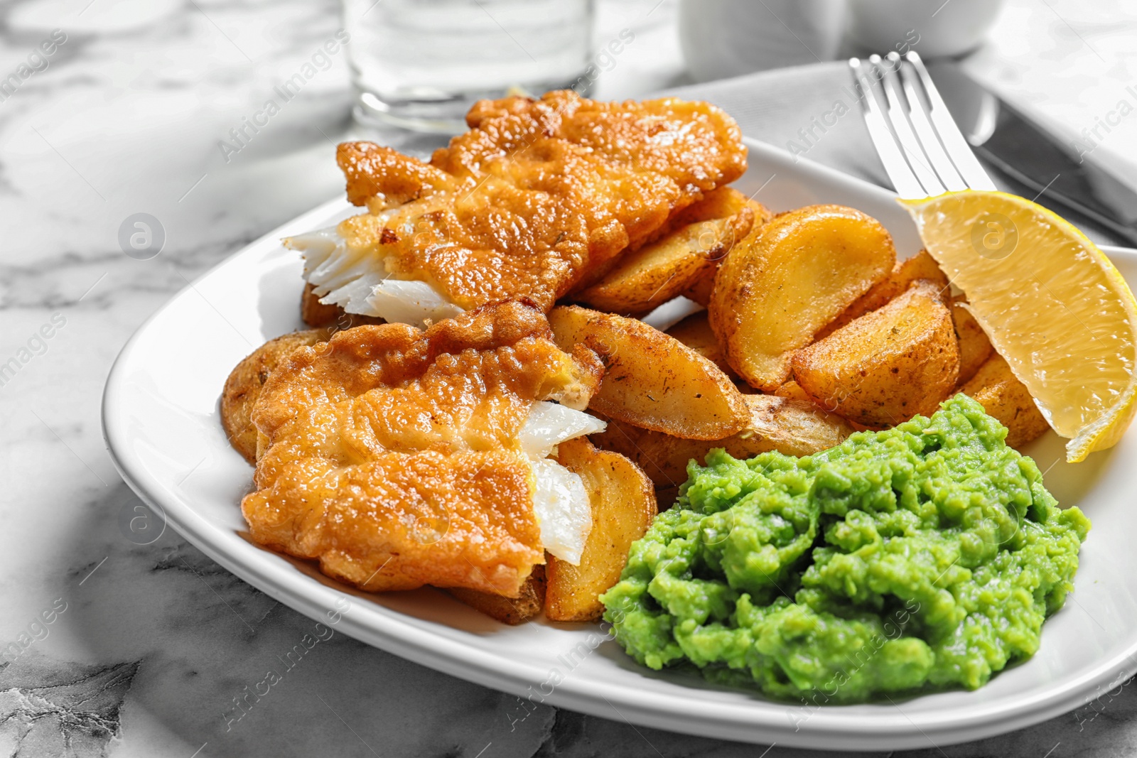 Photo of Plate with British traditional fish and potato chips on marble table, closeup