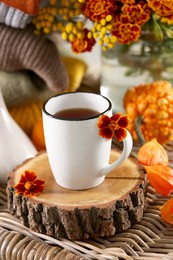 Photo of Cup of drink and autumn flowers on wicker table