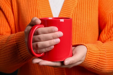 Photo of Woman holding red mug of drink, closeup