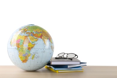 Photo of Globe, books and eyeglasses on wooden table against white background. Geography lesson