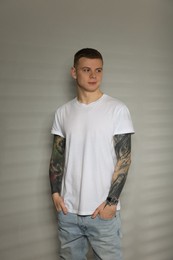 Photo of Young man with tattoos near light wall