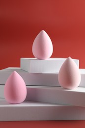 Photo of Stylish presentation of makeup sponges on red background