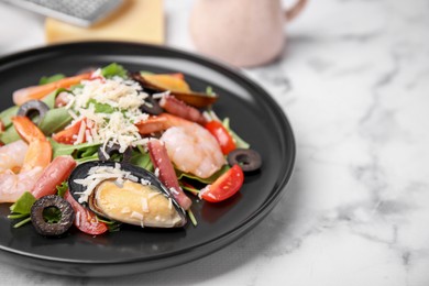 Plate of delicious salad with seafood on white marble table, closeup. Space for text