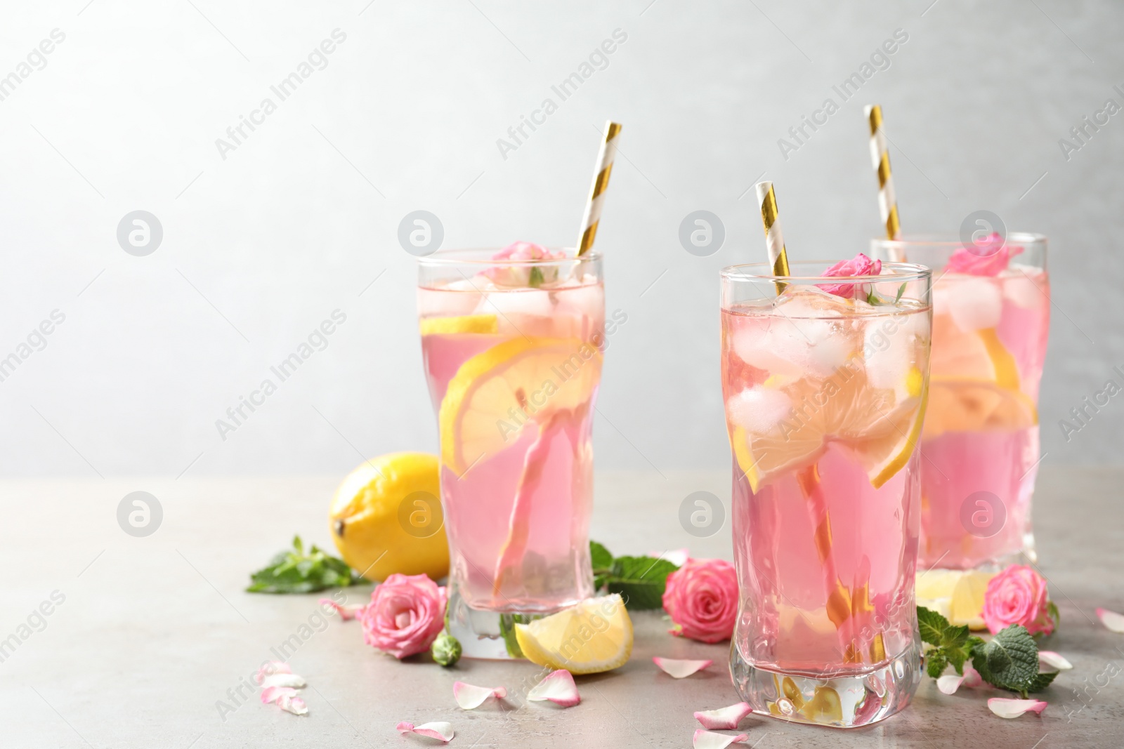 Photo of Delicious refreshing drink with rose flowers and lemon slices on light grey table