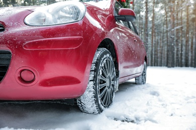 Photo of Modern car on snowy road in winter forest. Space for text