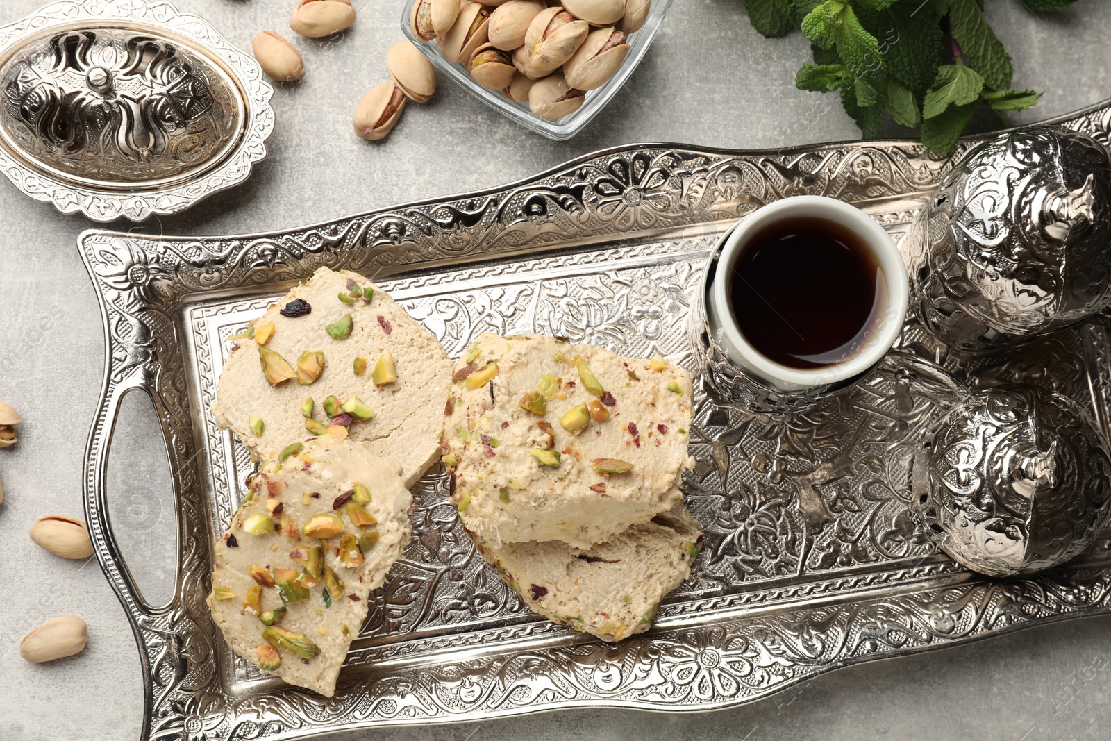 Photo of Tasty halva with pistachios served on grey table, flat lay