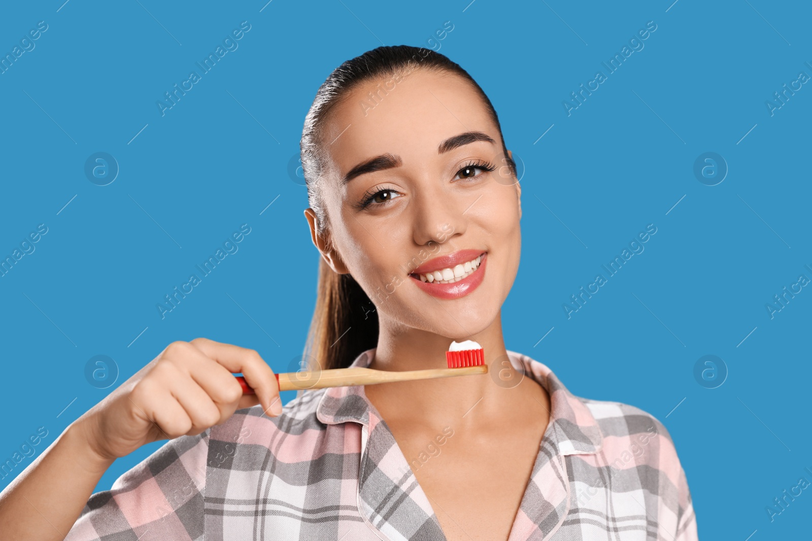 Photo of Woman holding toothbrush with paste on blue background