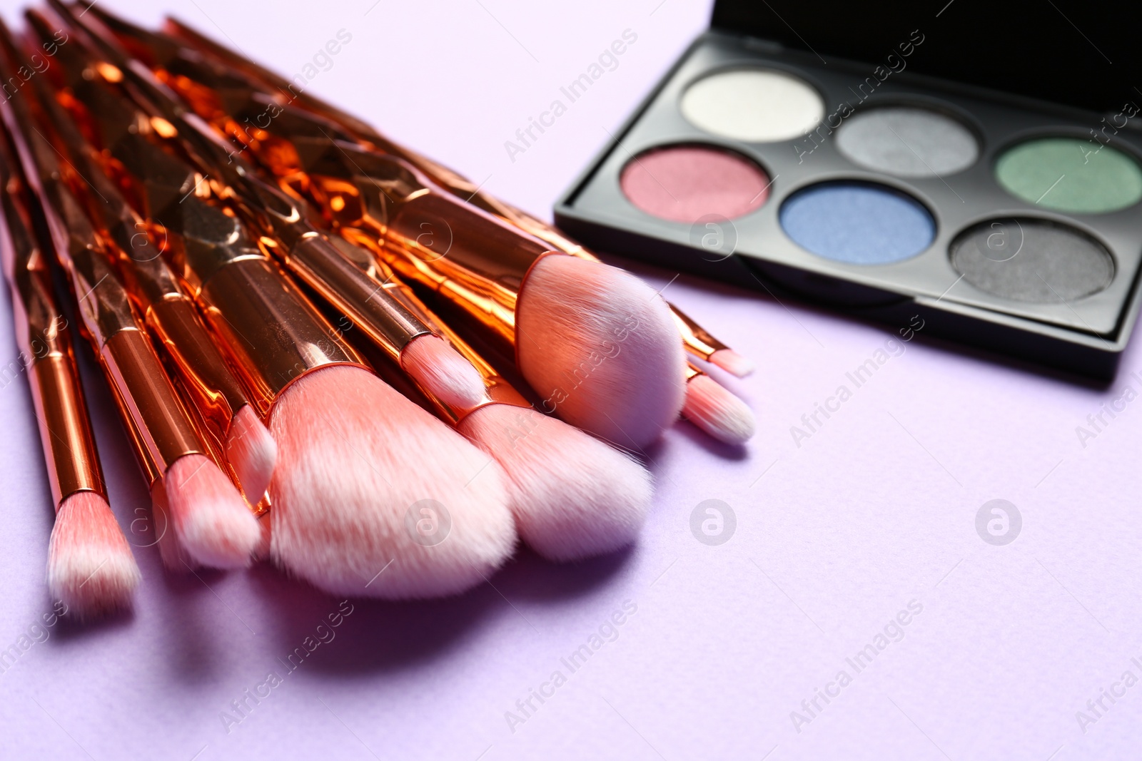 Photo of Professional makeup brushes and eye shadow palette on lilac background. Space for text