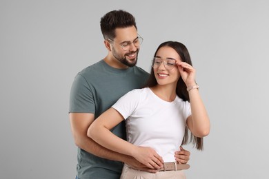 Beautiful couple wearing glasses on light gray background