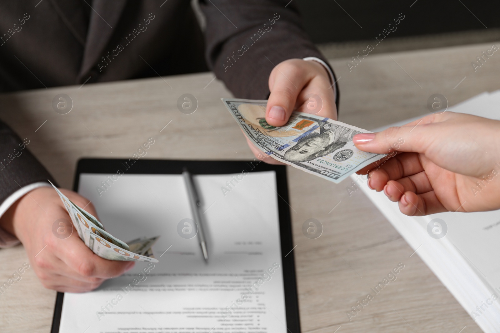 Photo of Man giving money to woman at light table, closeup. Currency exchange