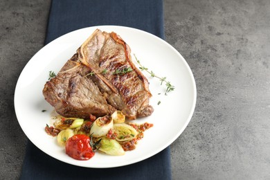 Delicious fried beef meat and vegetables on grey table