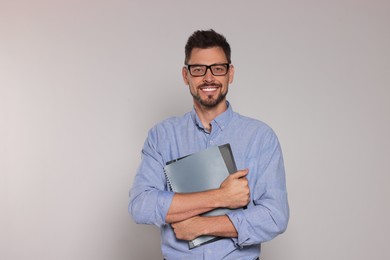 Photo of Happy teacher with glasses and stationery against beige background
