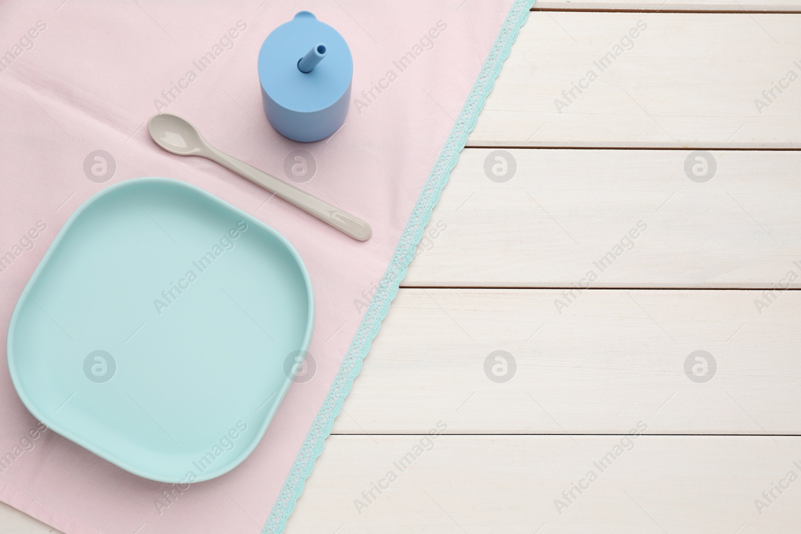 Photo of Set of plastic dishware on white wooden background, flat lay with space for text. Serving baby food