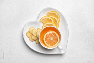 Plate with cup of tea, lemon and ginger on white background, top view