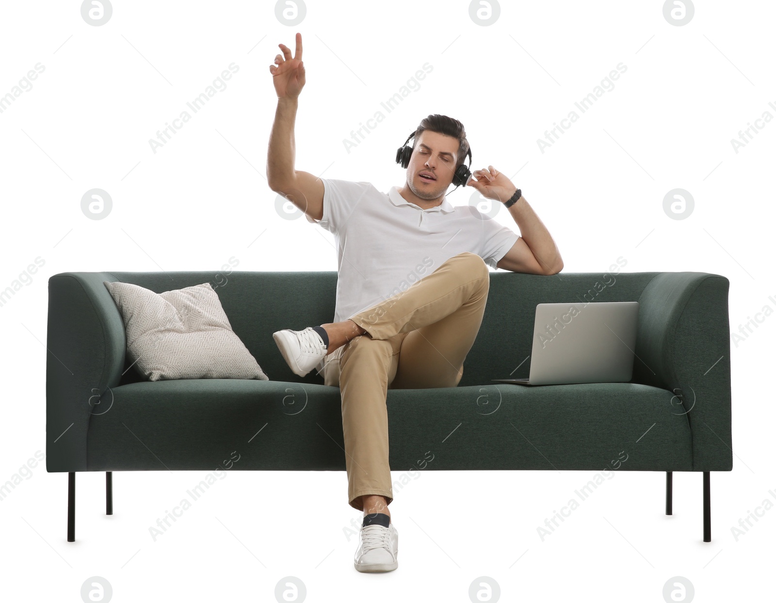 Photo of Man with laptop listening to music on comfortable green sofa against white background