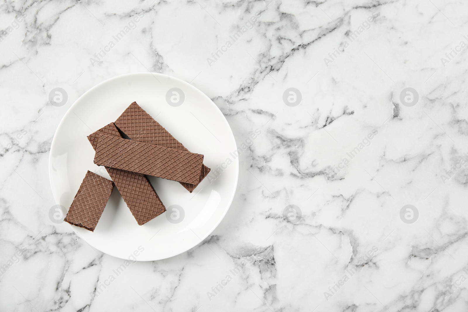 Photo of Plate of delicious chocolate wafers on marble background, top view. Space for text