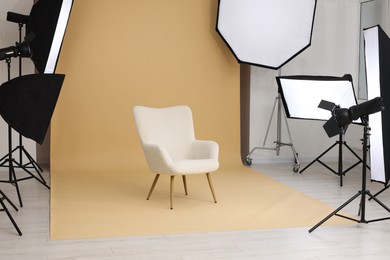Interior of modern photo studio with armchair and professional lighting equipment