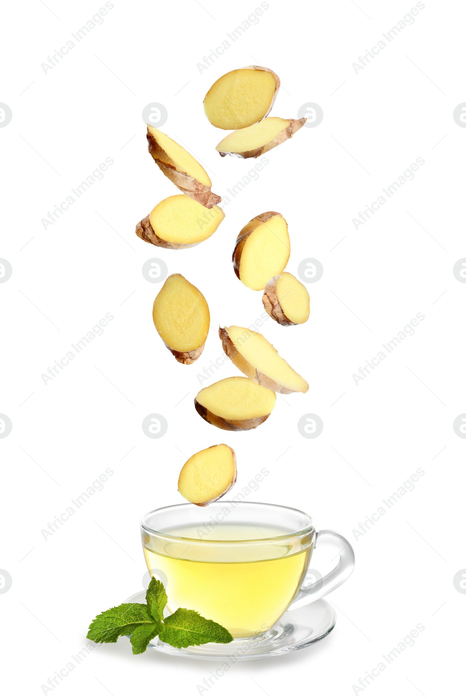 Image of Fresh sliced ginger falling into glass cup of tea on white background