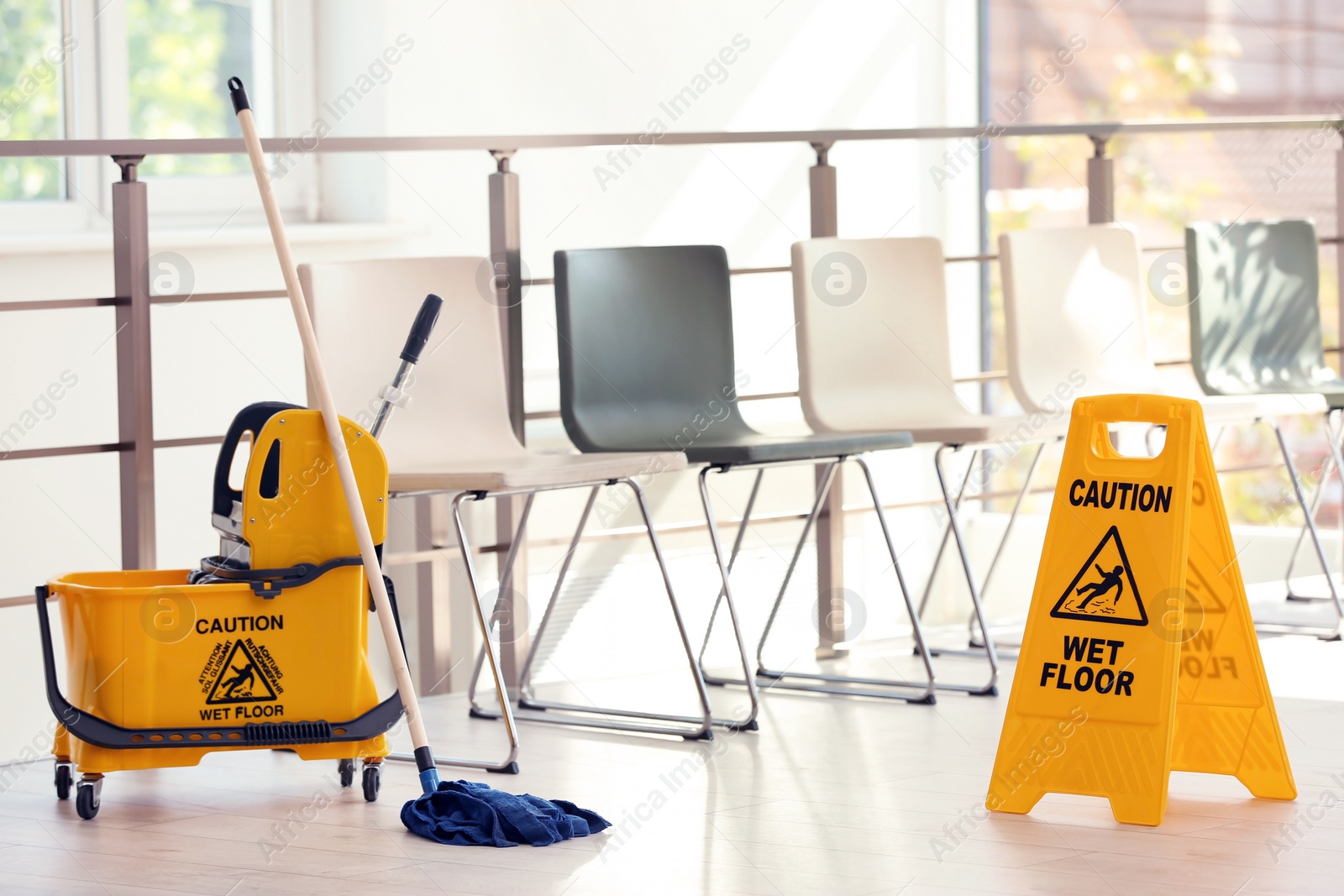 Photo of Safety sign with phrase Caution wet floor and mop bucket, indoors. Cleaning service