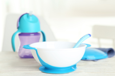 Photo of Set of plastic dishware on white wooden table indoors. Serving baby food