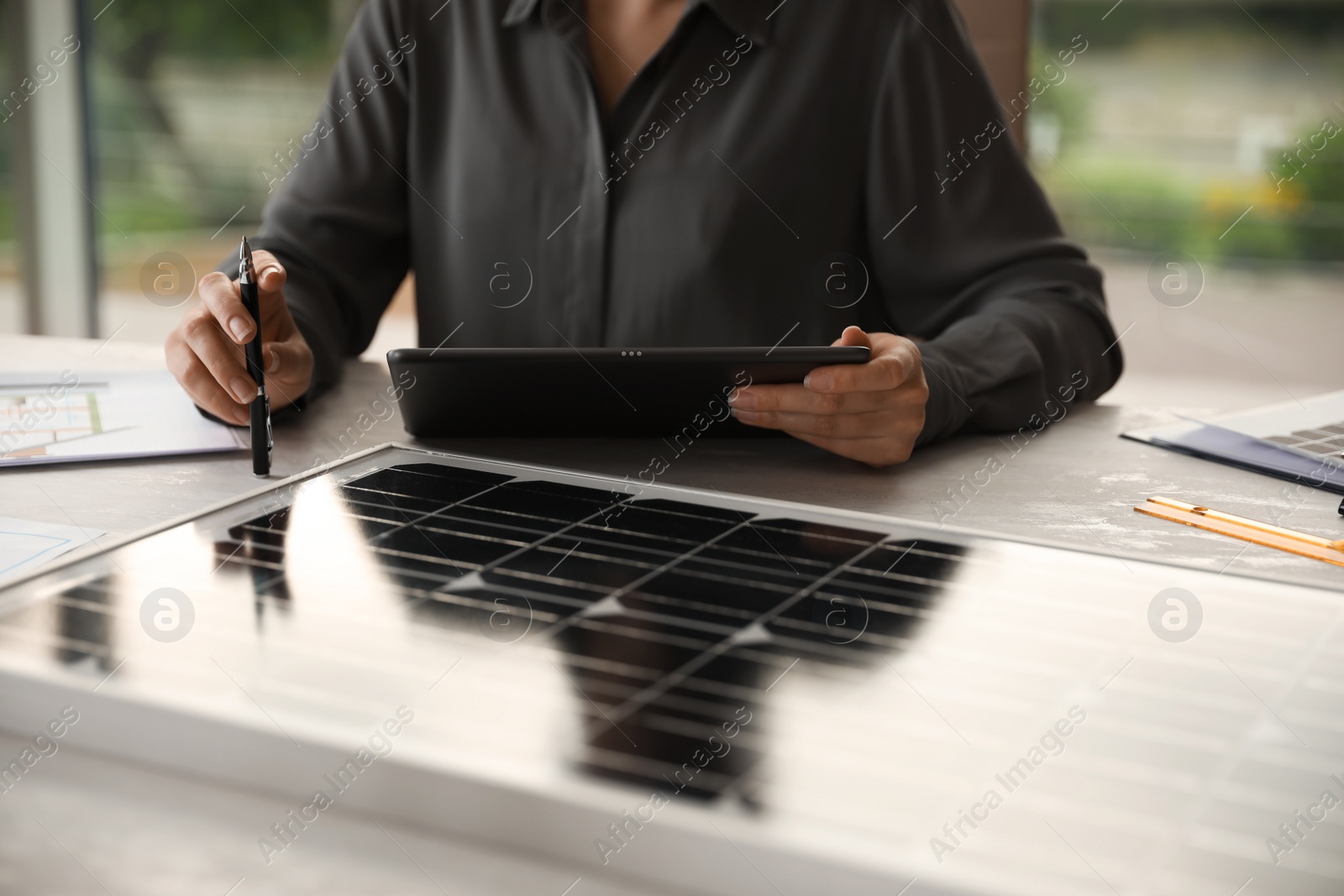 Photo of Woman working on project with solar panels at table in office, closeup