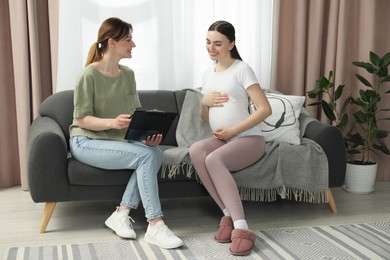 Doula working with pregnant woman on sofa at home. Preparation for child birth