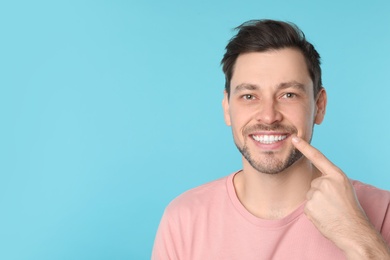 Photo of Smiling man with perfect teeth on color background. Space for text