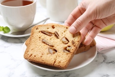 Woman with slice of pear bread at white marble table, closeup. Homemade cake