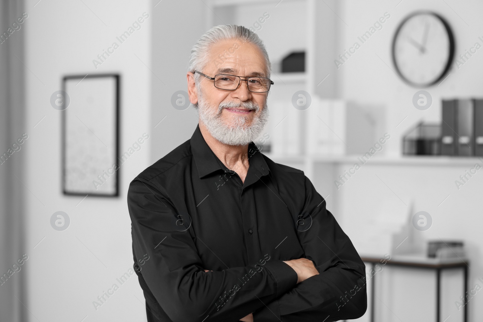 Photo of Portrait of handsome senior man in black shirt and eyeglasses at home