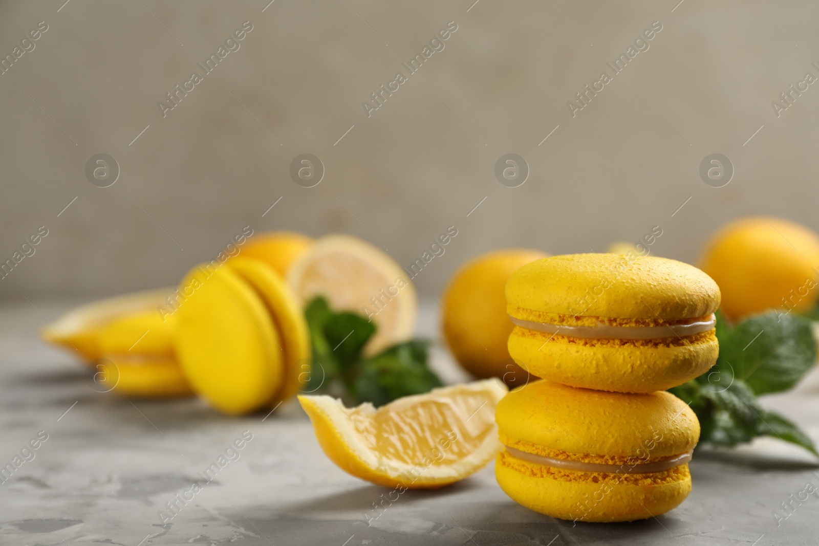 Photo of Delicious yellow macarons and lemon on light grey table. Space for text