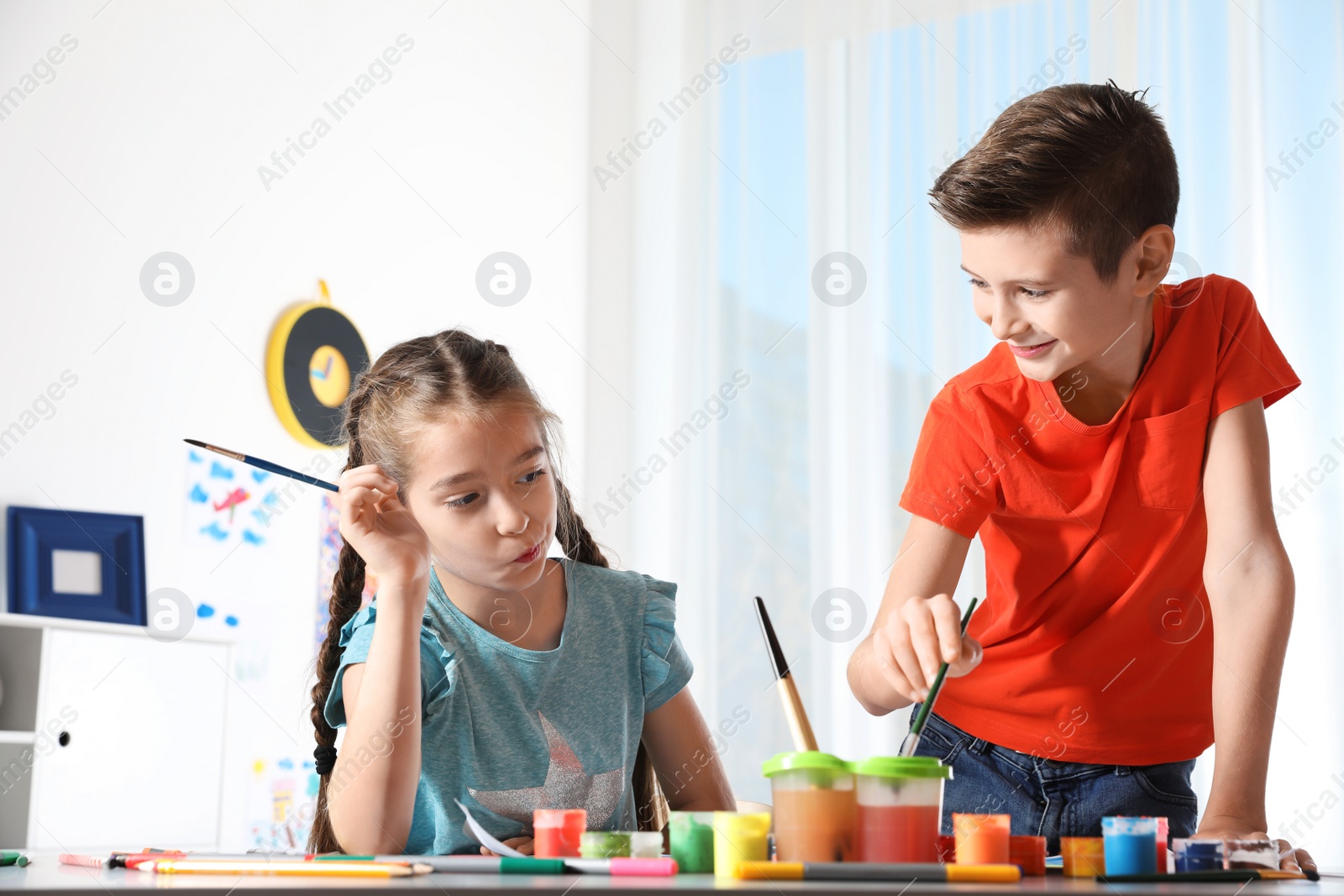 Photo of Little children painting picture at table indoors