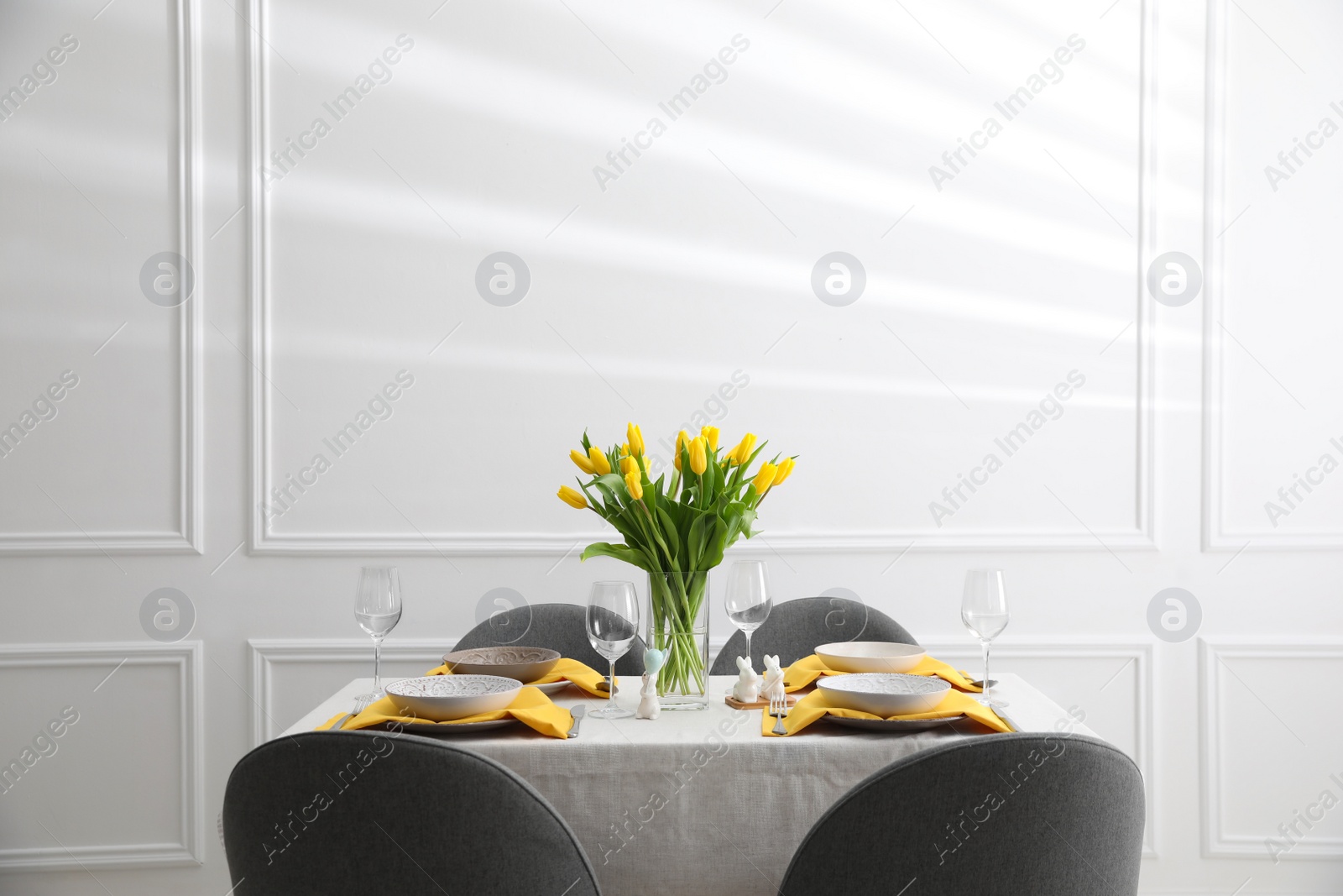 Photo of Beautiful Easter table setting with yellow tulips indoors