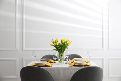 Photo of Beautiful Easter table setting with yellow tulips indoors