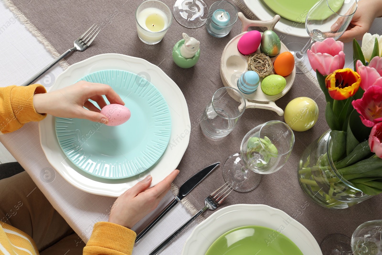 Photo of Woman setting table for festive Easter dinner at home, top view