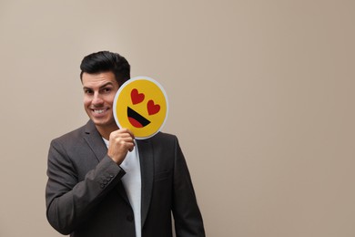 Photo of Happy man holding card with drawn smiling face on beige background. Space for text