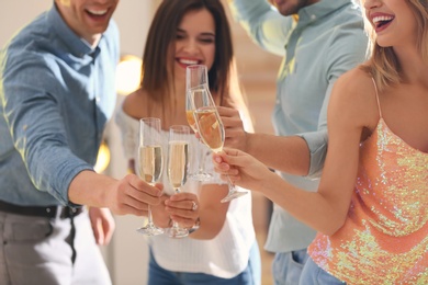 Photo of Friends clinking glasses with champagne at party indoors